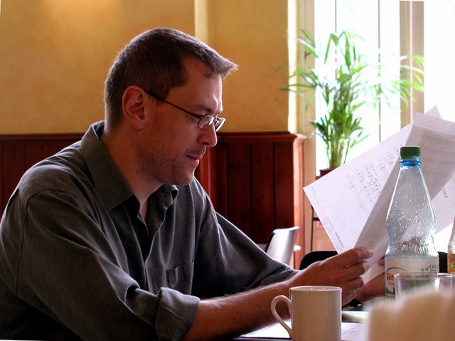 Photo of Stephen Jones looking at some documents whilst sitting at a table.
